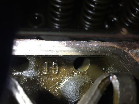 1996 Ford Bronco - A close-up view of an engine cylinder head shows the number "19" cast into the metal, along with oil residue and part of a valve spring ass…