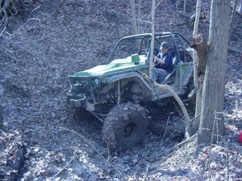 1992 Ford Bronco - Off-road vehicle navigates a challenging muddy and wooded terrain.