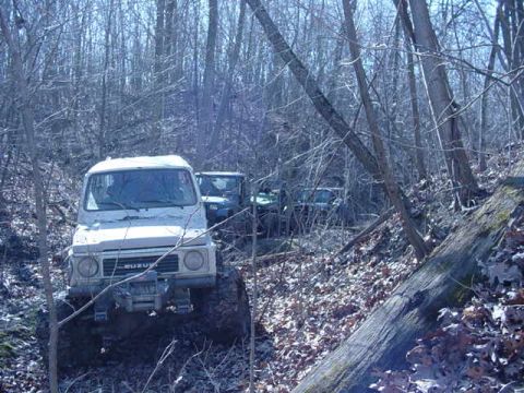 1992 Ford Bronco - Multiple SUVs navigate a wooded trail, with one vehicle prominently in the foreground.