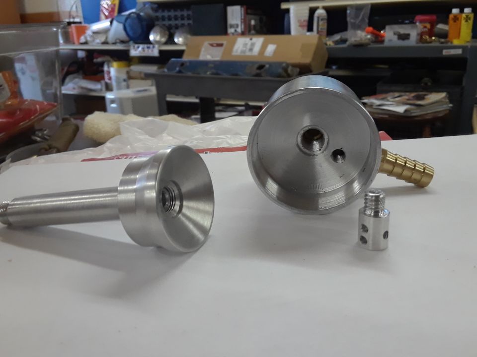 Machined aluminum parts including a cylinder with a hose barb and a smaller threaded part, and a long rod with a flared end.