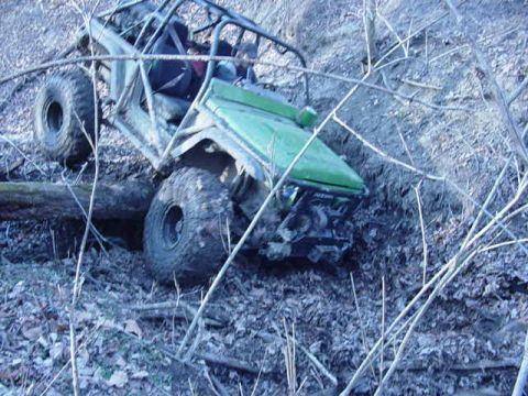 1992 Ford Bronco - An off-road vehicle navigates a steep, muddy terrain with dense foliage.