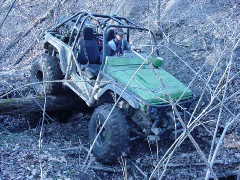 1992 Ford Bronco - This heavily modified off-road vehicle navigates a challenging, wooded trail.