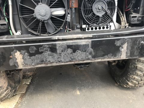 1989 Ford Bronco - The front bumper of a black vehicle shows significant damage and peeling paint, with two large cooling fans visible behind it. The vehicle…