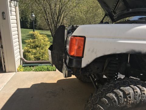 1989 Ford Bronco - The front corner of a white Ford Bronco is visible, showing the driver's side fender, headlight, and a large aftermarket fender flare. The…