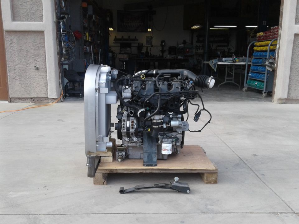 Diesel engine and radiator on a pallet outside a garage.