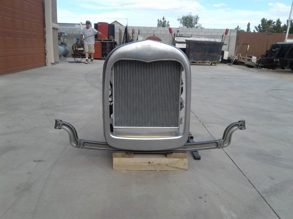 Front view of a classic car radiator and grille assembly on wooden blocks.