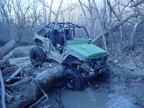 1992 Ford Bronco - This off-road vehicle navigates a challenging muddy terrain, getting stuck on a fallen tree.
