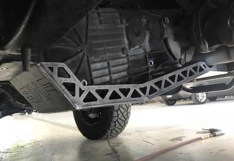 1995 Ford Bronco - A custom metal skid plate with triangular cutouts is installed underneath the transmission of a vehicle, likely an SUV or truck. The skid p…