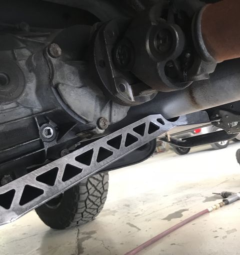 1995 Ford Bronco - Underside view of a vehicle's drivetrain, showing a transfer case, driveshaft, and a custom triangular support brace mounted below the exha…