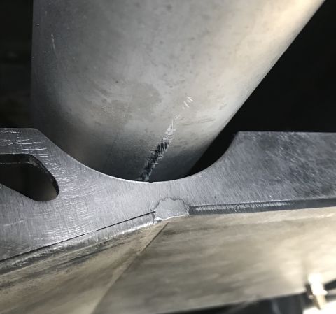 1995 Ford Bronco - A close-up view shows a cracked metal pipe resting on a metal bracket. The pipe has visible damage and appears to be part of a vehicle's ex…