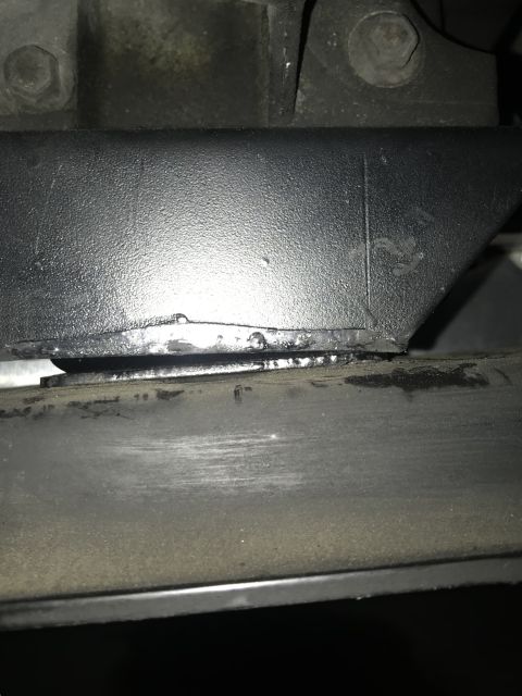 1995 Ford Bronco - A close-up view shows a black metal bracket with some wear and tear, resting on a dark, textured surface. The bracket appears to be part of…