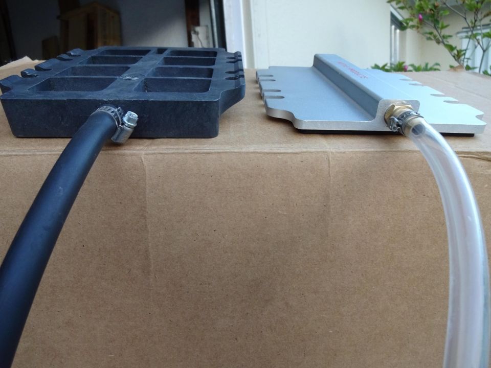 Black and silver molds with hoses attached, resting on cardboard.