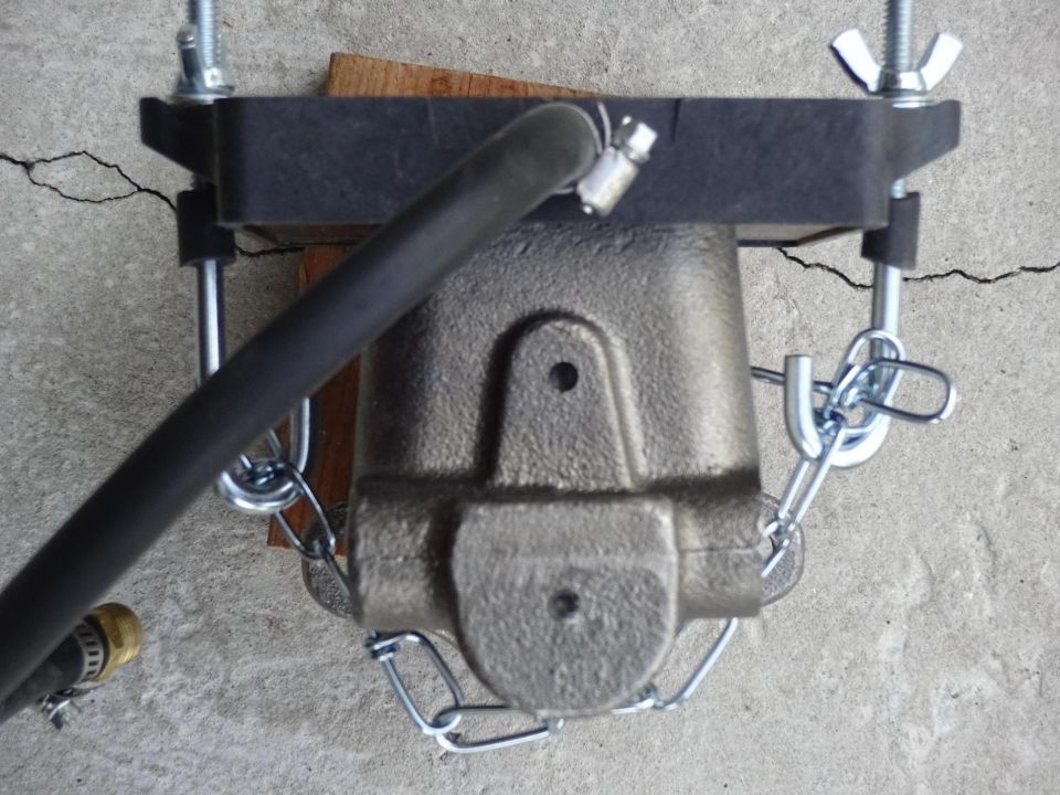 Brake master cylinder assembly with hose and chains attached to a bracket.