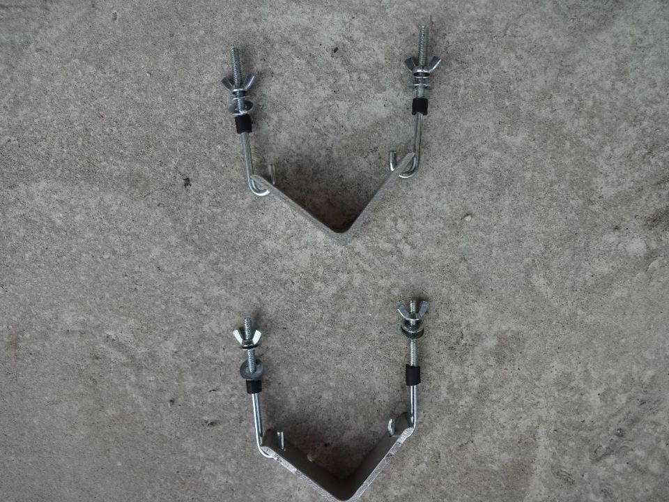 Two metal brackets with wing nuts and bolts on a concrete surface.
