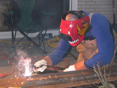 1986 Ford Bronco - A person is welding metal outdoors, wearing protective gear and a decorative welding mask.
