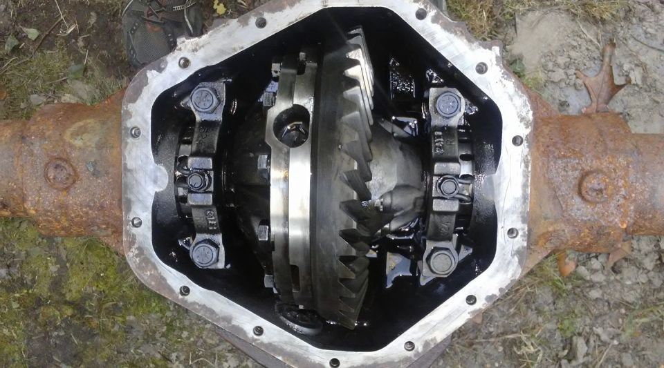 Open differential assembly with gears coated in oil, showing rust on the axle housing.