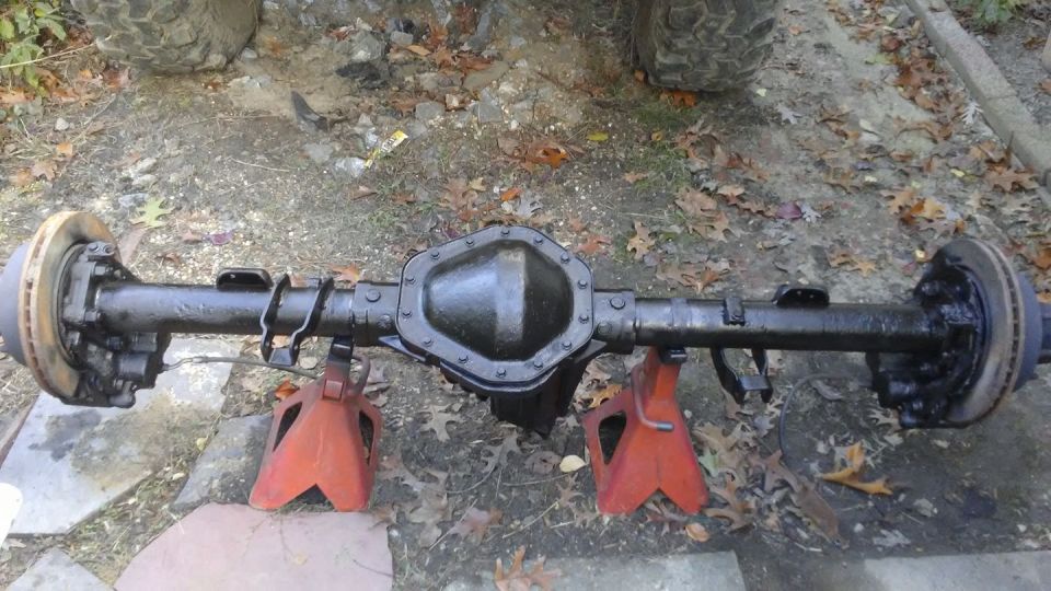 Black rear axle assembly with disc brakes on red jack stands.