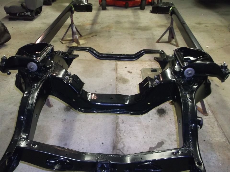 Black painted vehicle frame with front suspension components on jack stands