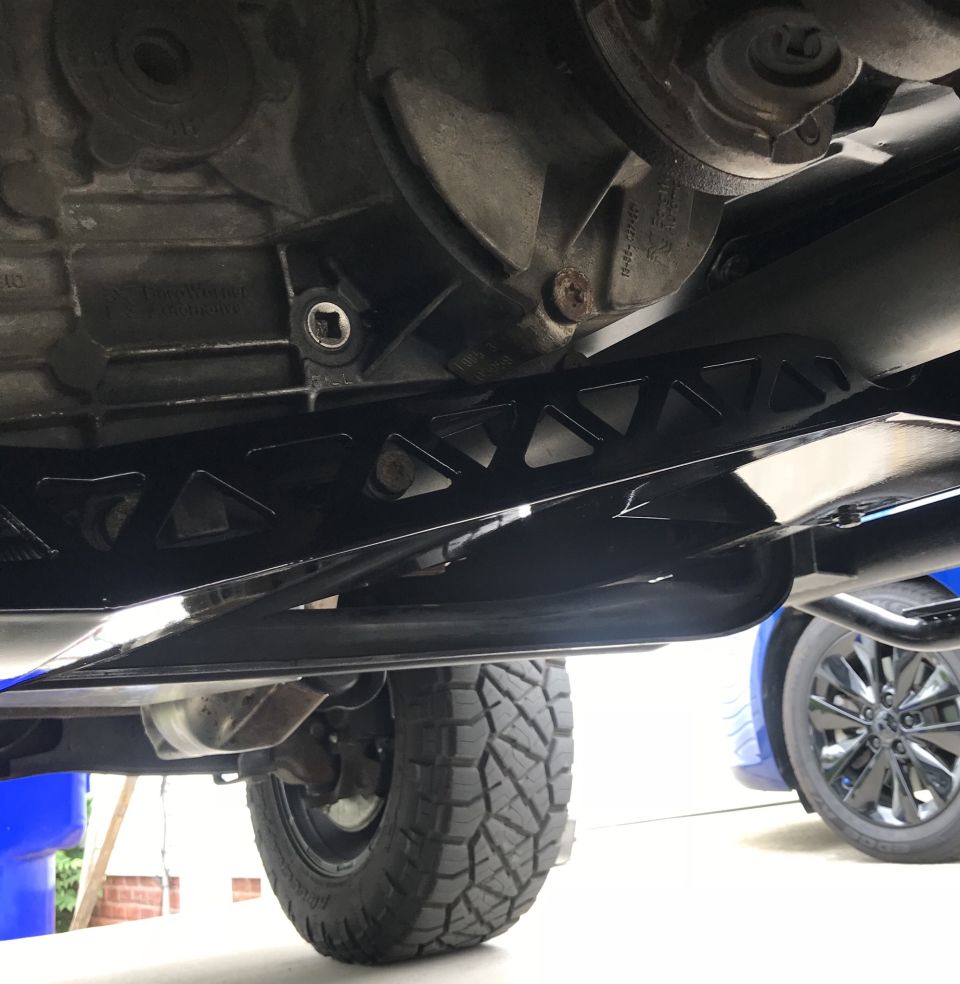 Underside view of a black triangular skid plate on a vehicle.