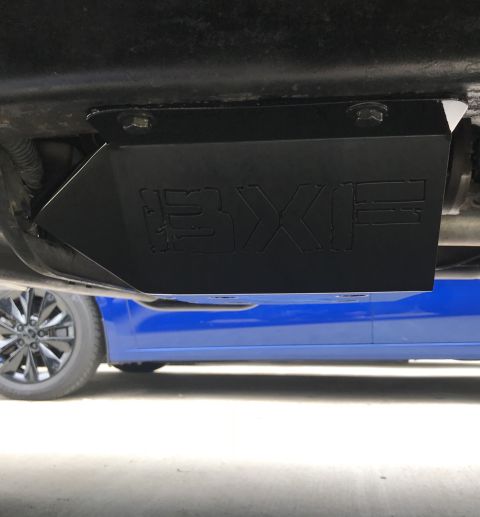 1995 Ford Bronco - A black metal skid plate with the "BXF" logo is bolted to the underside of a vehicle. A blue car is visible in the background.