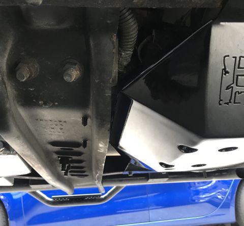 1995 Ford Bronco - The underside of a vehicle shows a black skid plate with a cut-out logo, attached to a black metal frame. Below the frame, a bright blue bo…
