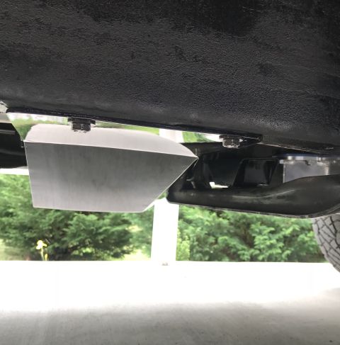 1995 Ford Bronco - A close-up, low-angle view of a shiny metal skid plate bolted to the underside of a black vehicle. The skid plate is angled and appears to…