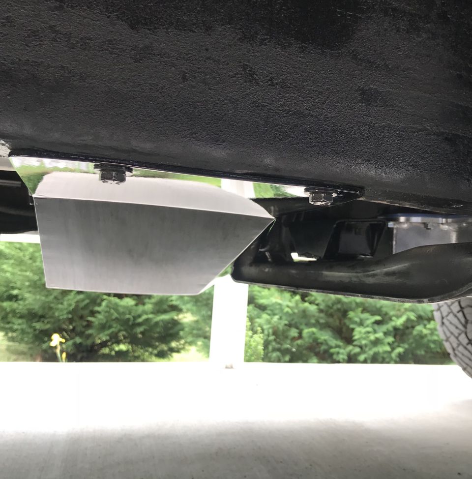 Shiny metal skid plate bolted to the underside of a black vehicle.
