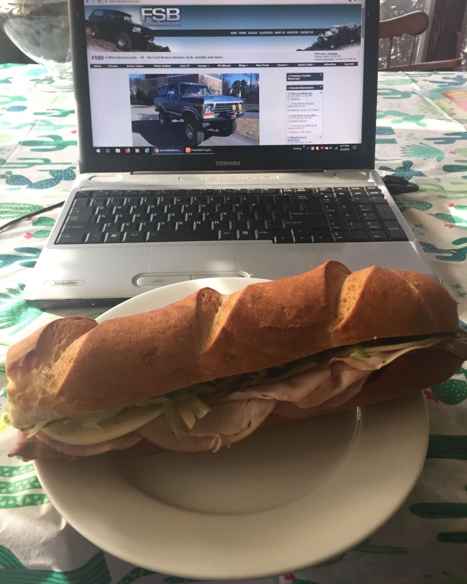 Laptop open to FSB website showing Ford trucks, with a sandwich on a plate in front