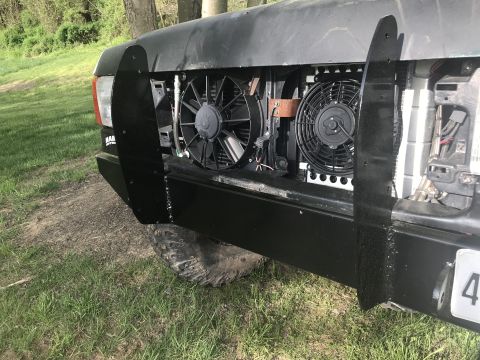 1989 Ford Bronco - This black SUV's front end shows extensive aftermarket modifications, including winch guards and dual electric fans.