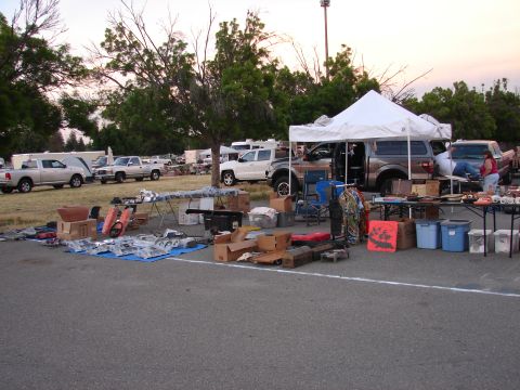 1973 Ford Ranchero - An outdoor market displays various vehicle parts and several pickup trucks under a white canopy.