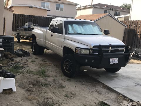 1997 Dodge 3500 - This white Dodge 3500 dually pickup truck is parked in a driveway, hitched to a boat on a trailer.