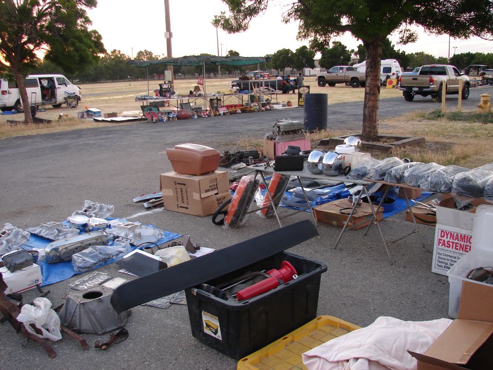 Car parts spread on pavement with a van in background