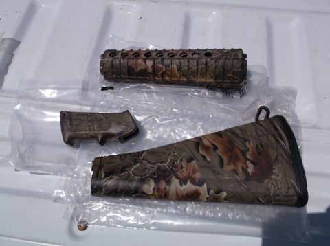 1995 Mercury Grand Marquis - Three camouflage rifle parts are visible, including a forend, pistol grip, and buttstock.