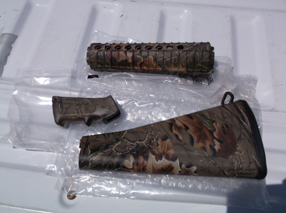 Camouflage rifle forend, pistol grip, and buttstock laid out on a white surface