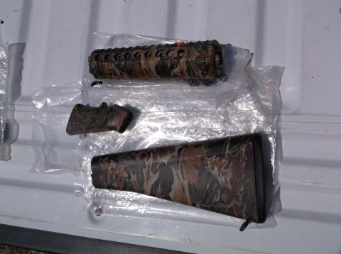 1995 Mercury Grand Marquis - These camouflage gun components are packaged separately on a white surface, possibly a truck bed.