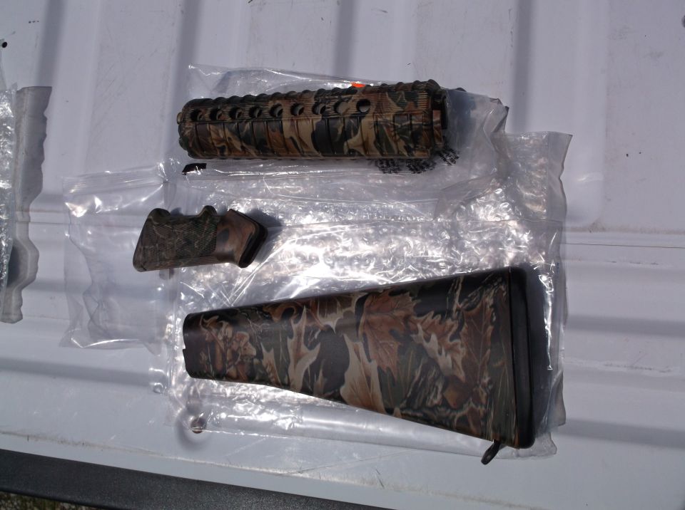 Camouflage rifle forend, pistol grip, and buttstock laid out on a white surface