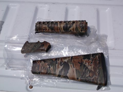 1995 Mercury Grand Marquis - Several camouflage-patterned gun parts are laid out on a white surface, appearing to be new and in packaging.