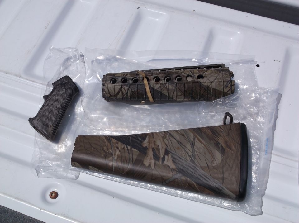 Camouflage gun stock and forend parts laid out on a white surface
