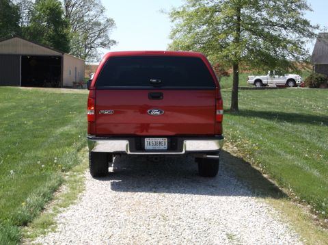 2008 Ford F-150 - A red Ford F-150 pickup truck is parked on a gravel driveway, with a white pickup truck in the background.