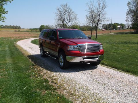 2008 Ford F-150 - A red pickup truck is parked on a gravel driveway in a rural setting.
