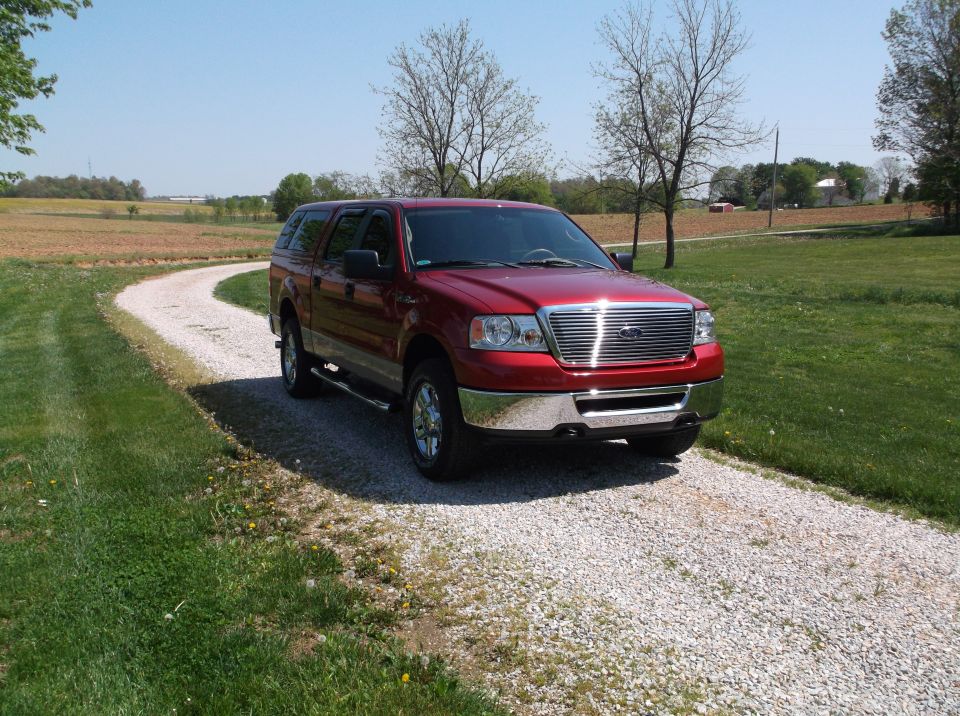 Red pickup truck with camper shell on a gravel driveway