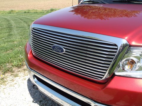 2008 Ford F-150 - Close-up of a red Ford F-150 truck's chrome grille and headlight assembly.