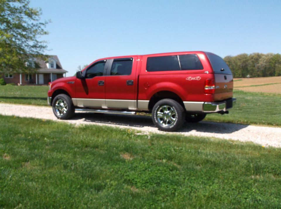 Red 2008 Ford F-150 pickup truck with a cap, parked on a gravel driveway