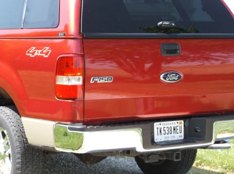 2008 Ford F-150 - The rear of a red Ford F-150 pickup truck is shown, a chrome bumper and a 4x4 decal on the fender.