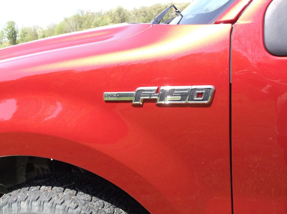 Close-up of a red Ford F-150 fender with an F-150 badge. The Supermotors.net watermark is visible