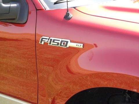2008 Ford F-150 - Close-up of the F-150 XLT badge on the fender of a red 2008 Ford F-150.
