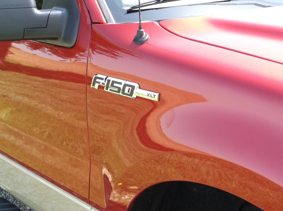 Close-up of F-150 XLT badge on a red truck fender