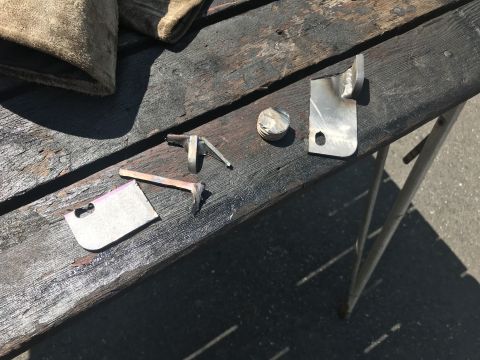 1989 Ford Bronco - Various metal parts are laid out on a wooden surface, possibly for repair or fabrication.
