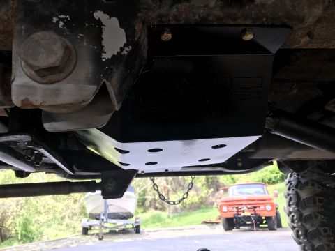 1989 Ford Bronco - The photo shows the undercarriage of a vehicle, focusing on a newly installed skid plate, with other vehicles in the background.