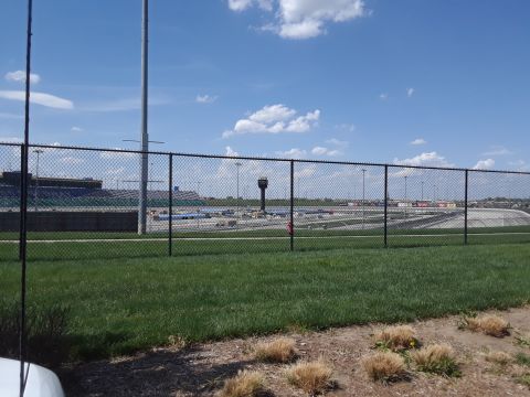 1994 Ford Bronco - A view of a race track facility, including a control tower and grandstands, seen through a fence on a sunny day.